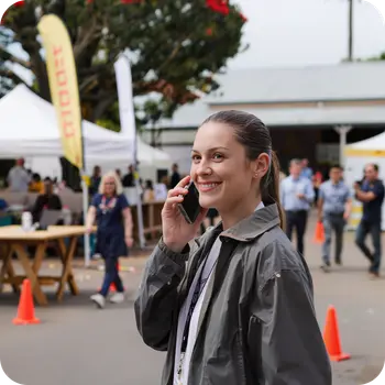Woman on a phone call at an outdoor event site.