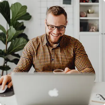 Man smiling as he hosts webinar on laptop in a home office.